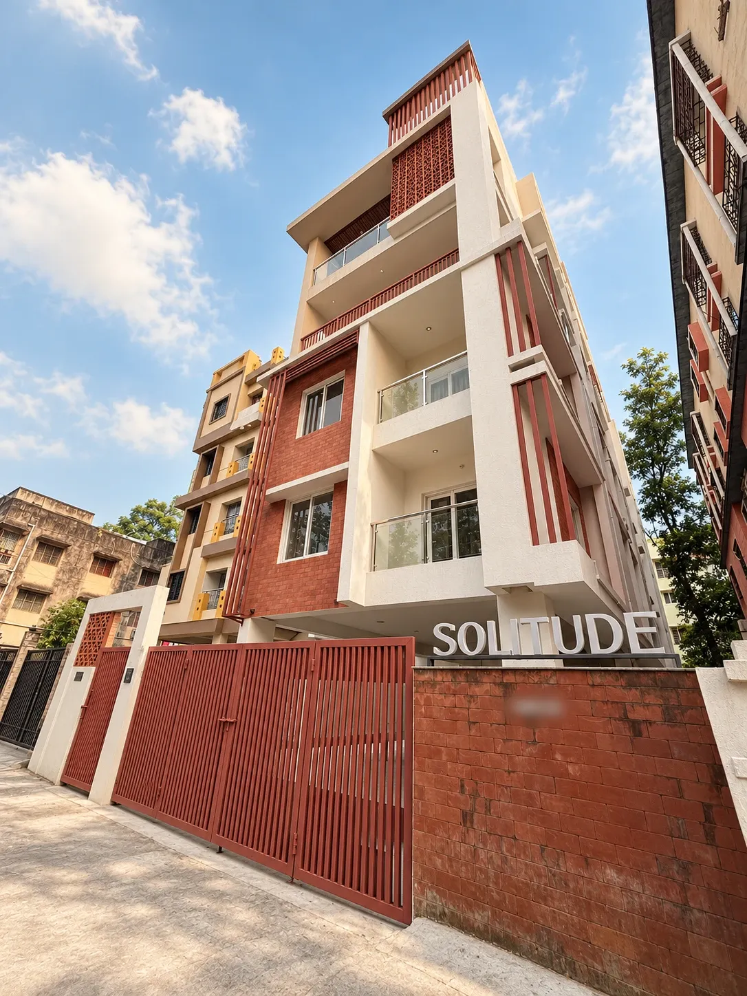 The Solitude Residency: a terracotta and cream building with the SOLITUDE sign on its gate, under a blue sky